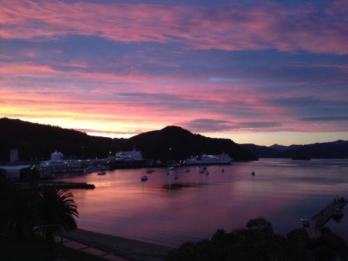 a sunset over a body of water with boats in it at Picton Waterfront Penthouse in Picton