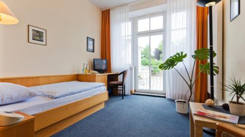 a bedroom with a bed and a desk and a window at Hotel Villa Subklew in Ostseebad Sellin