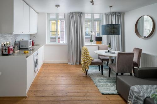 a kitchen and a living room with a table and chairs at Square Mile Residences in London