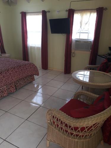 a bedroom with a bed and a table and two windows at Apartment Unforgetable Gardens in Falmouth