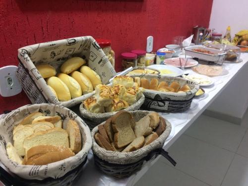 una mesa cubierta con cestas de pan y otros alimentos en Trevo De Arraial pousada em cabo frio, en Cabo Frío