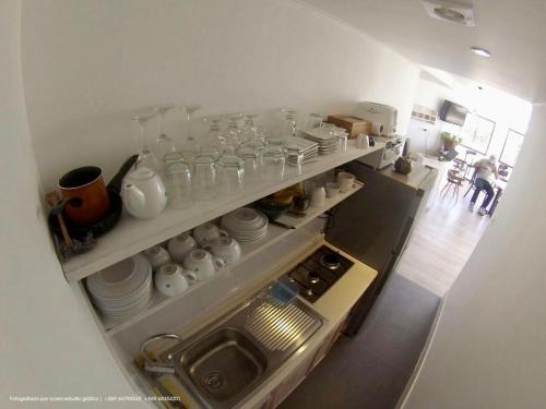 a kitchen with shelves filled with dishes and glasses at Hostal CKAIR in Bahia Inglesa