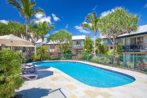 a swimming pool with palm trees and buildings at Beach Breakers Resort in Sunrise Beach