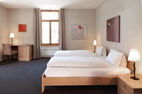a hotel room with two beds and a desk at Hotel und Naturresort Handeck in Guttannen