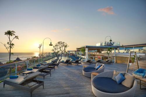 a deck with couches and chairs and the ocean at ASTON Canggu Beach Resort in Canggu