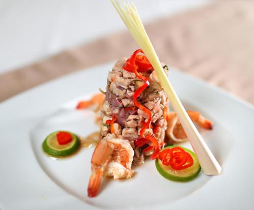 a white plate topped with meat and vegetables with chopsticks at Puri Saron Hotel Baruna Beach Lovina in Lovina
