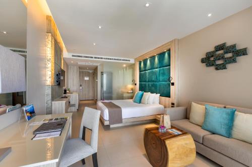 a hotel room with a bed and a couch at Cape Sienna Phuket Gourmet Hotel & Villas - SHA Extra Plus in Kamala Beach