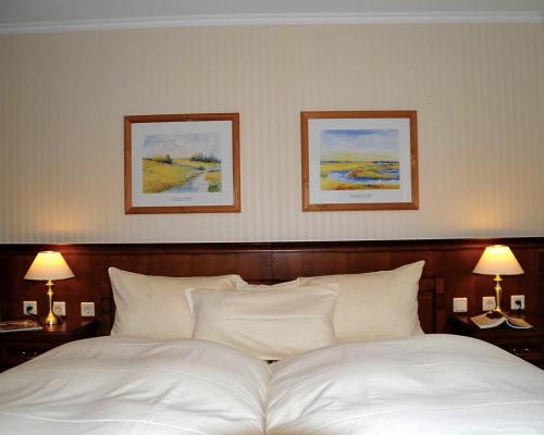 a bedroom with a white bed with two pictures on the wall at Waldhotel Rheinbach in Rheinbach