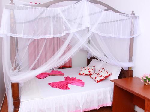 ein Bett mit roten und weißen Kissen und einem Baldachin in der Unterkunft Moon Glow Guest in Mirissa