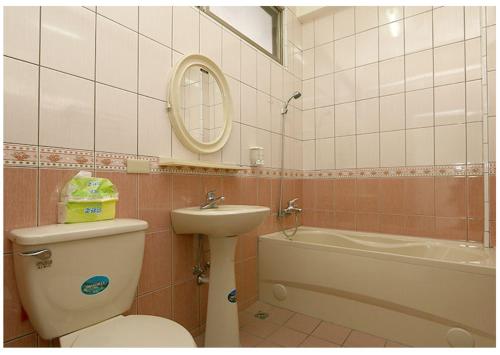 a bathroom with a toilet and a sink and a tub at Hsin Sheng Taitung in Taitung City