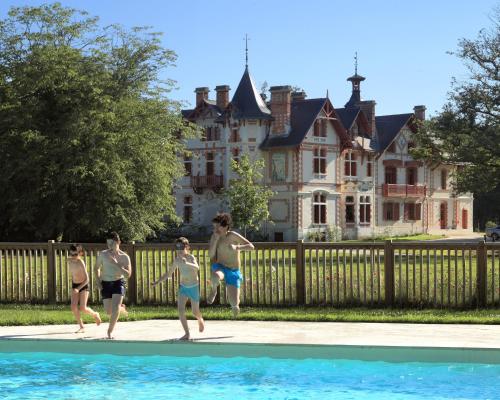 un groupe de personnes jouant dans une piscine en face d'une maison dans l'établissement Domaine de la Trigalière, à Ambillou