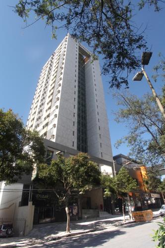 a tall white building with trees in front of it at Transamerica Belo Horizonte Lourdes in Belo Horizonte