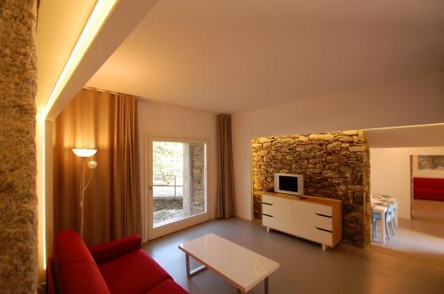ギッファにあるRustico Modernoの赤いソファと石壁のリビングルーム