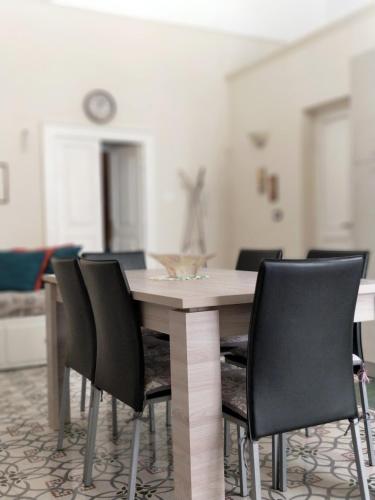 a dining room with a wooden table and black chairs at Appartamento Manfredi in Manfredonia