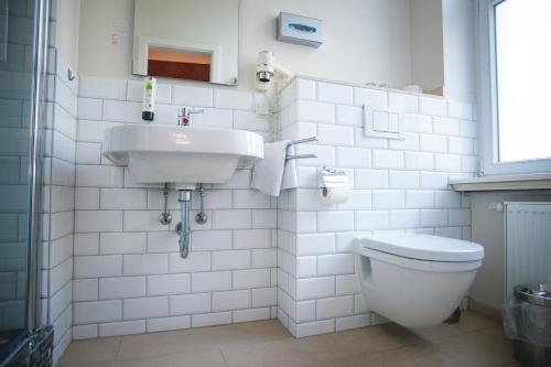 a white bathroom with a sink and a toilet at Hotel Alexander in Wiesbaden