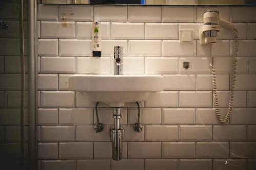 a sink in a bathroom with white tiled walls at Hotel Alexander in Wiesbaden