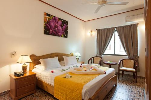 1 dormitorio con 1 cama grande con manta amarilla en Orchid Self Catering Apartment en La Digue