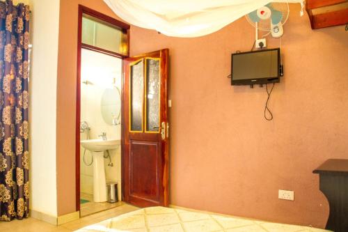 a bathroom with a toilet and a television on the wall at Hotel Gorilla's Nest Entebbe in Kitende