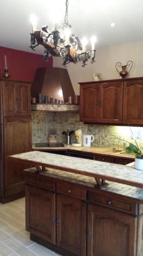 une cuisine avec des placards en bois et un lustre dans l'établissement Gite de la ferme du couvent, à Boran-sur-Oise