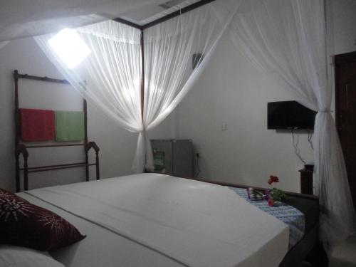 a bedroom with a bed with a white canopy at Sapara River Guest in Bentota