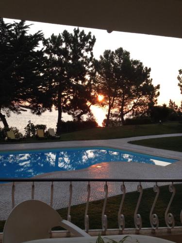 a view of a swimming pool from a balcony with the sunset at Troia Apartments in Troia