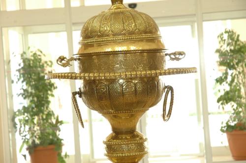 a gold vase sitting in front of some plants at El Mouradi Tozeur in Tozeur
