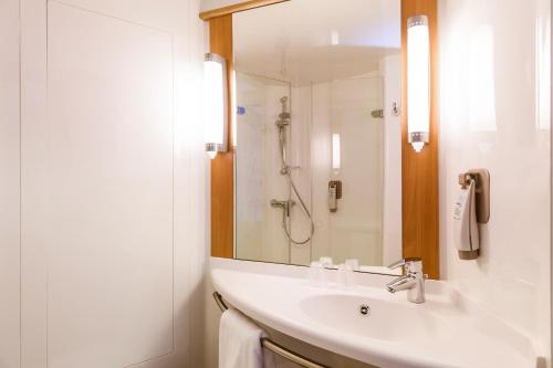 a white bathroom with a sink and a shower at ibis Karlsruhe Hauptbahnhof in Karlsruhe