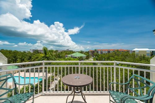 a balcony with a table and chairs and a pool at Sunrise Suites Tierra Bomba Suite #403 in Key West