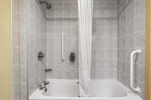 ein Badezimmer mit einer weißen Badewanne und einer Dusche in der Unterkunft Days Inn Watford Gap in Crick