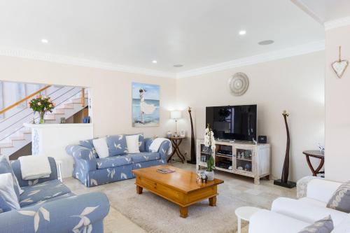 a living room with blue couches and a tv at Atlantic Beach Villa in Cape Town