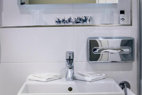 La salle de bains est pourvue d'un lavabo, d'un robinet et d'un miroir. dans l'établissement Hotel Die Port van Cleve, à Amsterdam