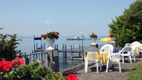 a row of white chairs and tables next to the water at Gasthaus Seeblick in Hagnau