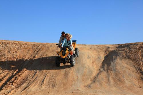 two people riding on a four wheeler on a dirt hill at El Mouradi Tozeur in Tozeur