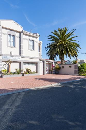 a white house with a palm tree in front of it at Atlantic Beach Villa in Cape Town