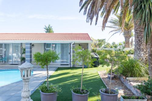 a house with a yard with palm trees and a swimming pool at Atlantic Beach Villa in Cape Town