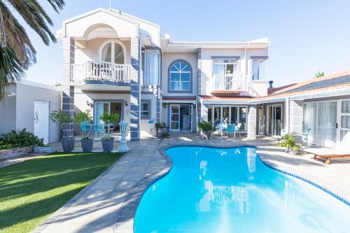 a villa with a swimming pool in front of a house at Atlantic Beach Villa in Cape Town
