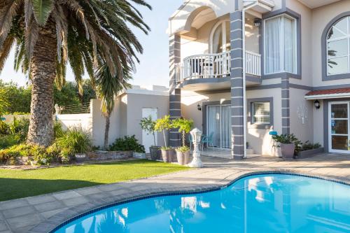 a villa with a swimming pool in front of a house at Atlantic Beach Villa in Cape Town