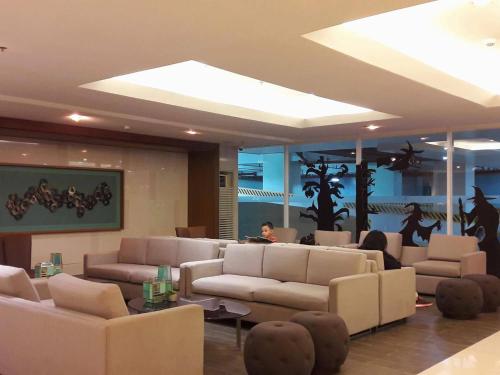 a lobby with couches and tables and a person in a room at De Luxe, Standard and Studio Suites -The Breeze Residences-close to Airport,Mall of Asia, US Embassy in Manila