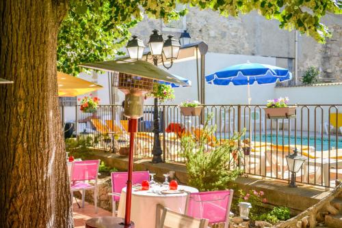 - une table avec des chaises, un parasol et une piscine dans l'établissement Logis Hôtel Restaurant Résidence, à Nissan-lez-Enserune