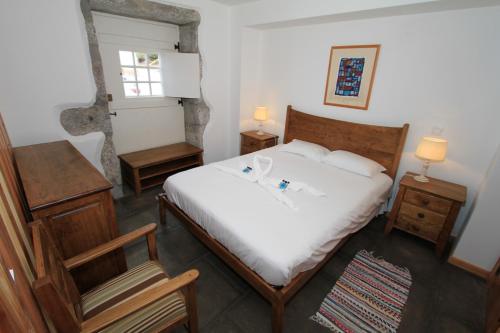 Schlafzimmer mit einem Bett mit weißer Bettwäsche und einem Fenster in der Unterkunft Casa Branca da Sociedade in Angra do Heroísmo