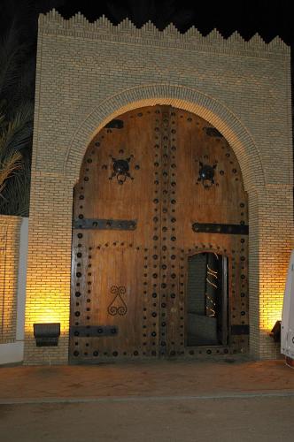 a large wooden door with two bugs on it at El Mouradi Tozeur in Tozeur