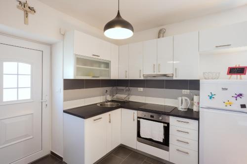 eine weiße Küche mit einer Spüle und einem Kühlschrank in der Unterkunft Apartment Pradini in Poljana