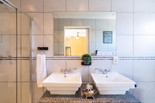 a bathroom with two sinks and a mirror at Atlantic Beach Villa in Cape Town