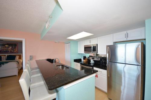 a kitchen with a stainless steel refrigerator and white cabinets at Sunrise Suites Cayo Coco Suite #208 in Key West