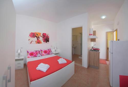 a bedroom with a red and white bed and a kitchen at Eolo Casa Vacanze in Torre Lapillo