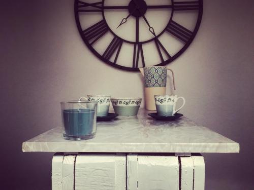 a table with cups and a large clock on a wall at Appartement Douces heures avec parking couvert privé in Le Locle
