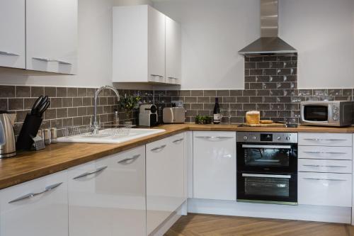 a kitchen with white cabinets and a black oven at The Apartments in Market Weighton