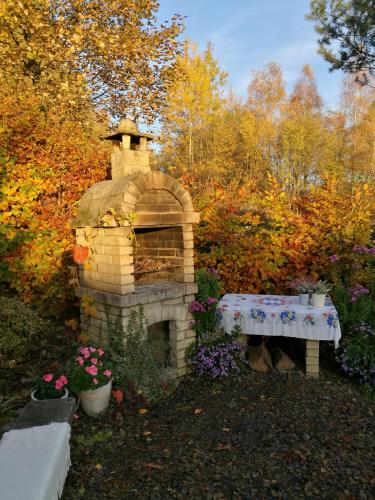 a stone fireplace with a bench in a garden at Przystań Gromadzyń in Ustrzyki Dolne