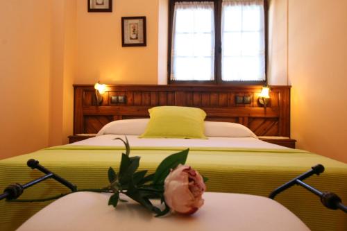 a bedroom with a bed with a flower on a table at Apartamentos Toraya in Hoz de Anero