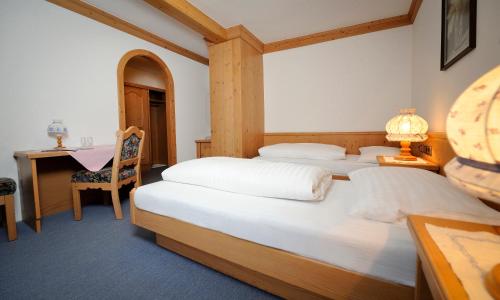 two beds in a room with a desk and a desk at Kalßwirt in Bad Aussee